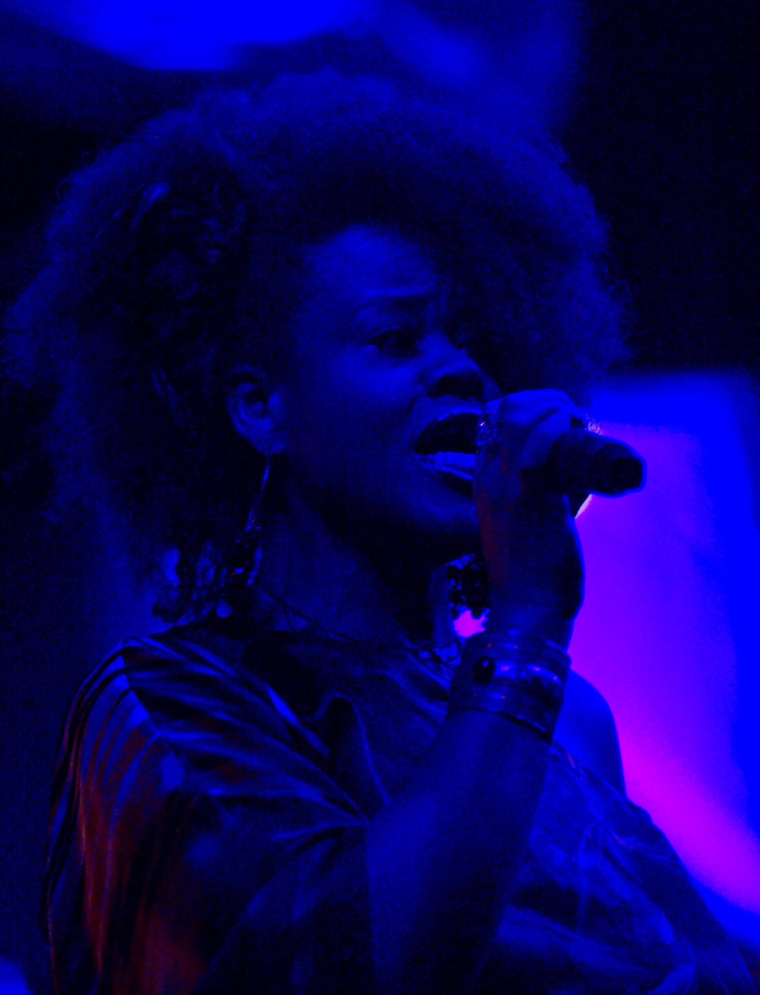 Lisa Mack singing on a vivid blue-lit stage