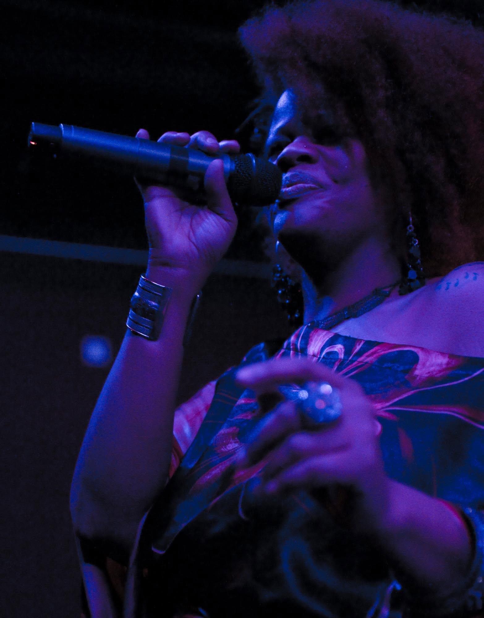 Lisa Mack singing beneath blue and violet stage lighting